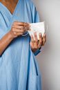 Anonymous African American female nurse wearing blue uniform and holding protective mask while standing on white background