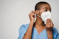 African American female doctor putting on protective mask