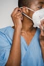 Crop African American female doctor in blue uniform adjusting protective mask and looking away