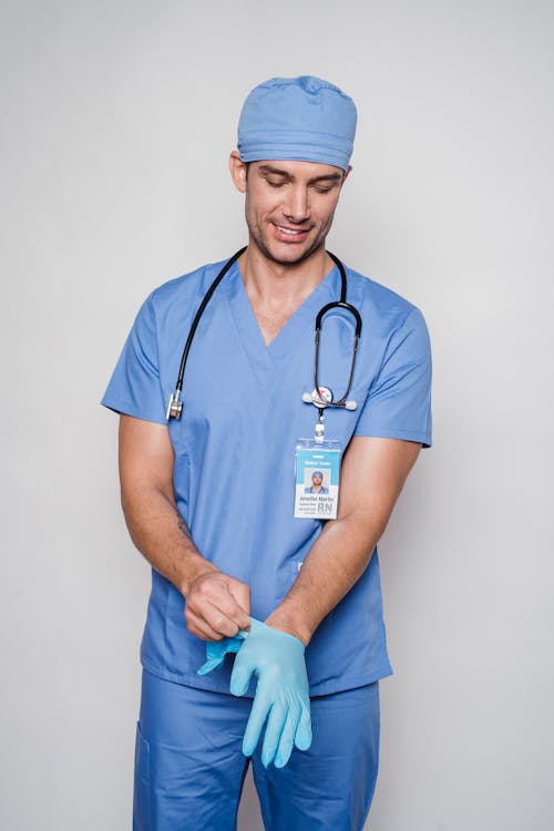 Male doctor in uniform putting on sterile gloves