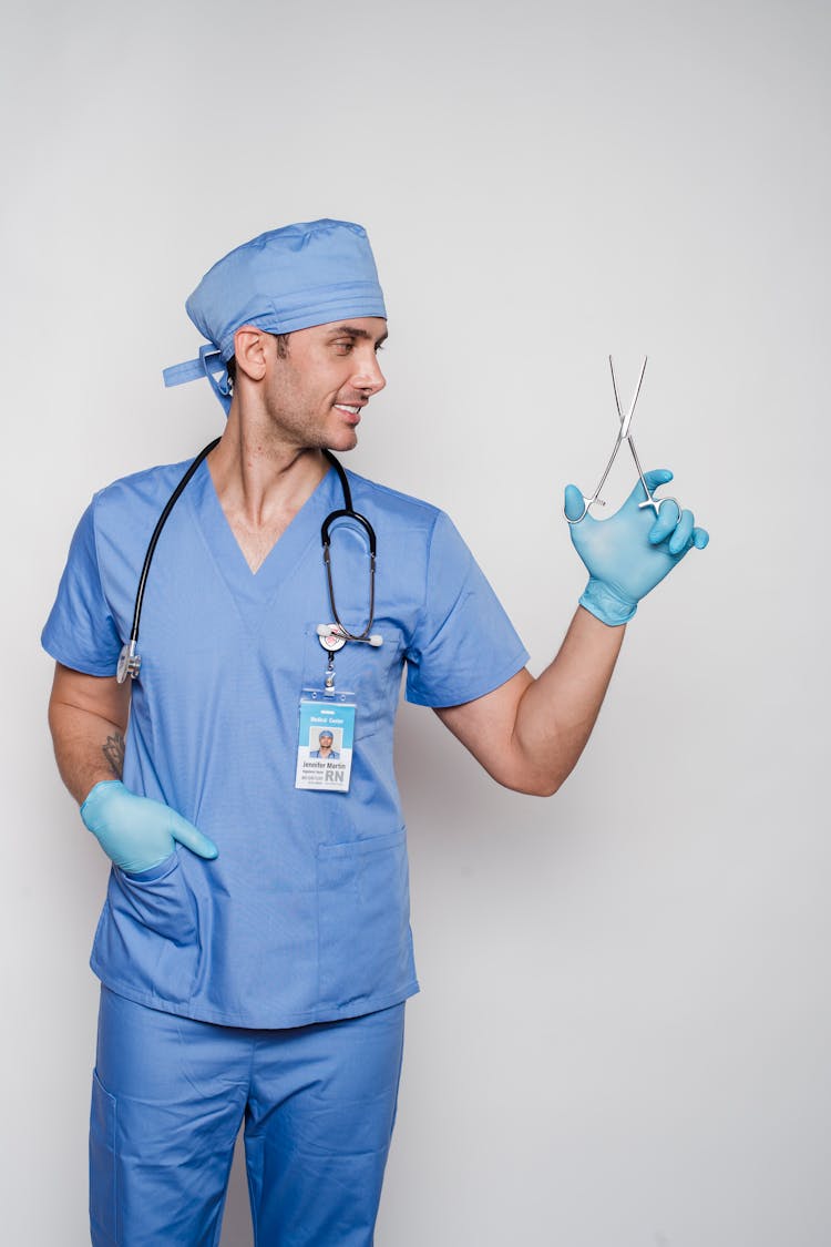 Professional Male Doctor In Uniform Showing Forceps