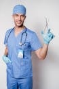 Professional specialist in blue medical clothes and latex gloves looking at camera and showing forceps