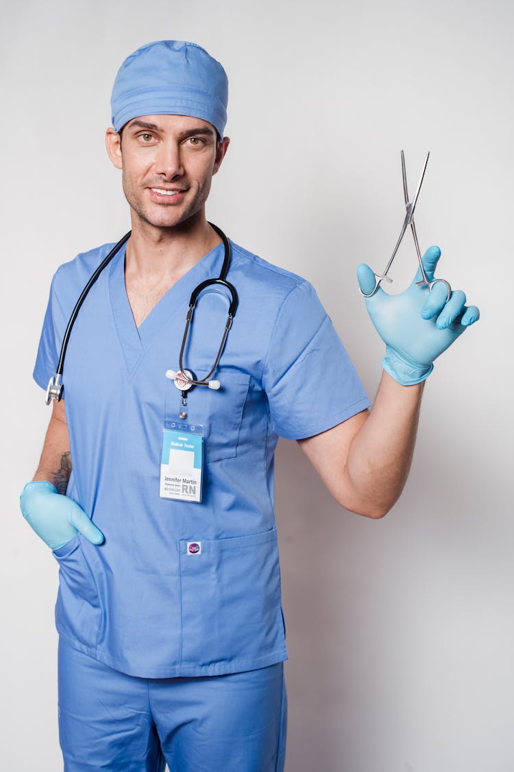 Male Doctor With Stethoscope In Uniform Demonstrating Forceps