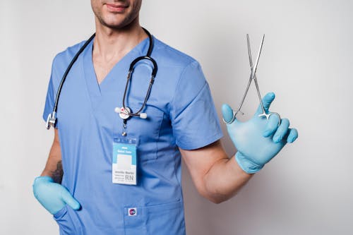Anonymous doctor in uniform and gloves with stethoscope and forceps