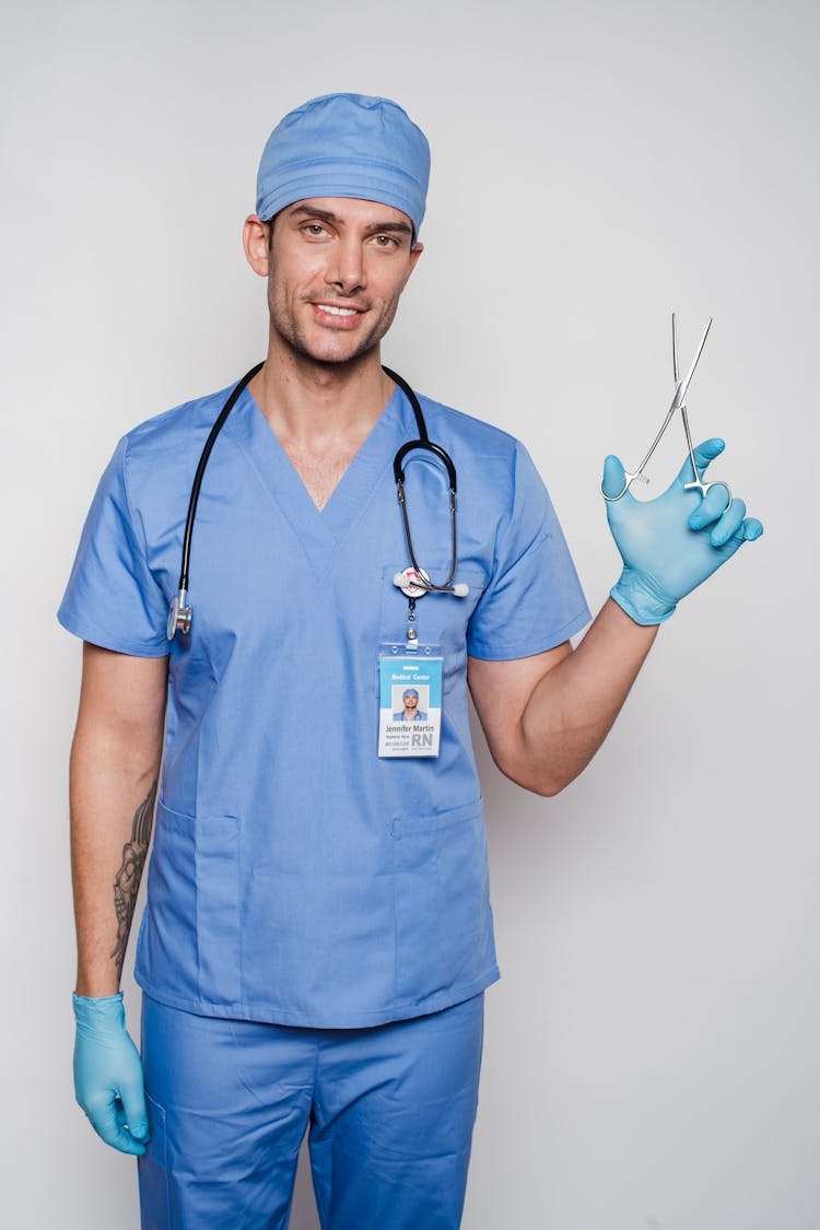 Male Doctor In Uniform And Gloves With Forceps And Stethoscope