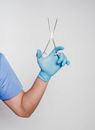 Unrecognizable male doctor in uniform and gloves with forceps