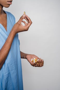 Close-up of a woman holding a variety of capsules in a blue robe against a white background.