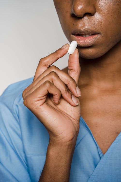 Free Faceless African American female patient taking pill Stock Photo