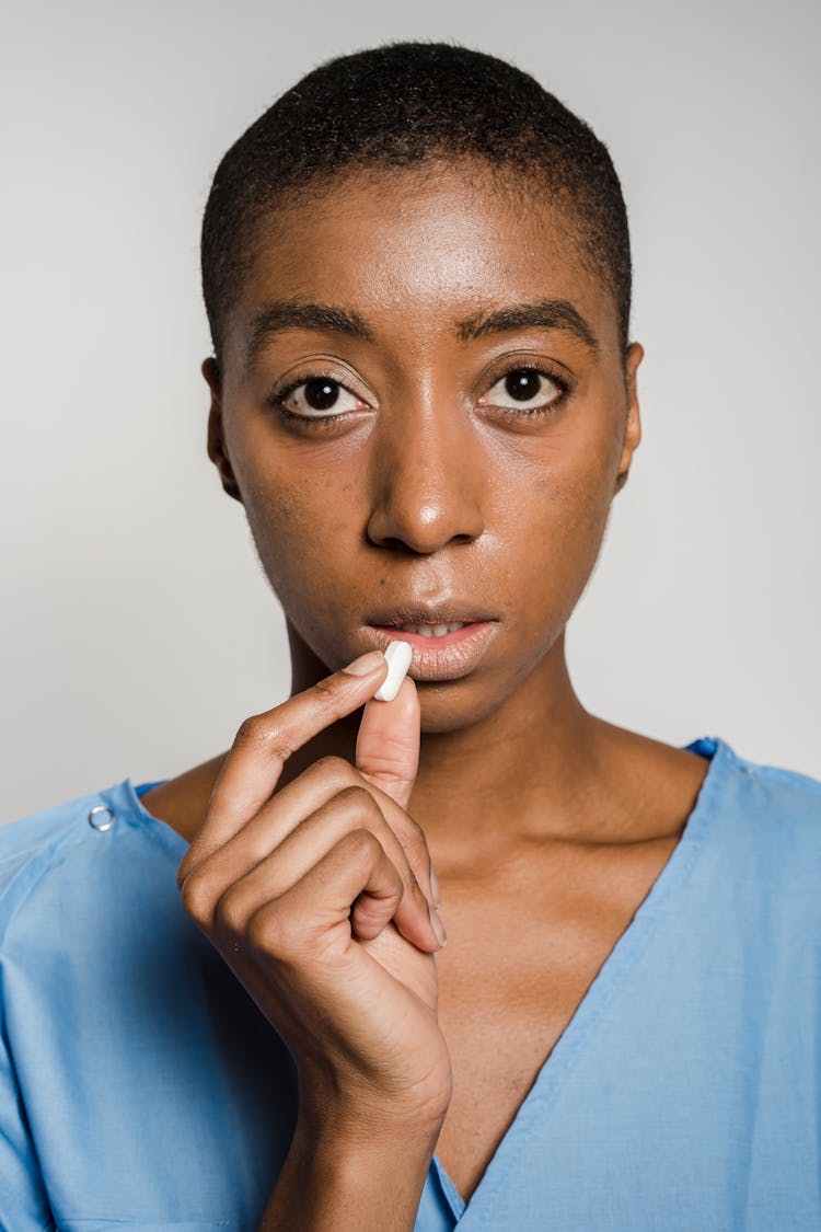 Serious African American Female Patient Taking Pill In Studio