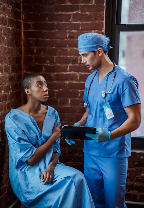 Doctor communicating with black patient in hallway of hospital
