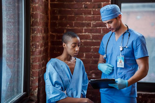 Free Doctor showing diagnosis to black woman patient in hallway of clinic Stock Photo