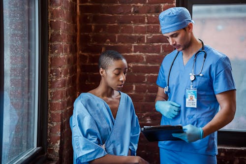 Doctor showing diagnosis to black woman patient in hallway of clinic