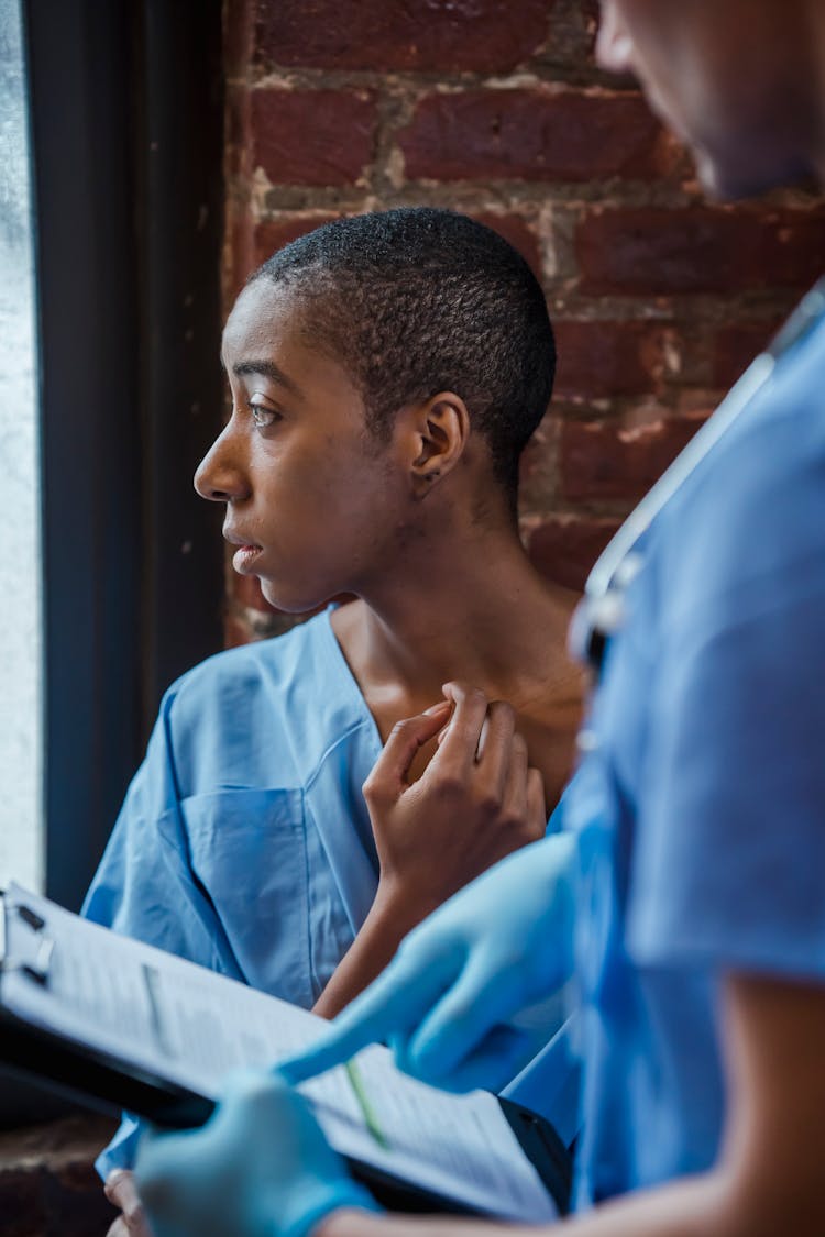 Doctor Standing Near Pensive Black Woman In Hallway Of Hospital