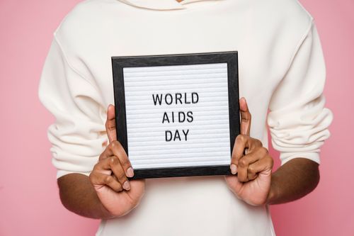 Free A person holding a sign with World AIDS Day message on pink background. Stock Photo