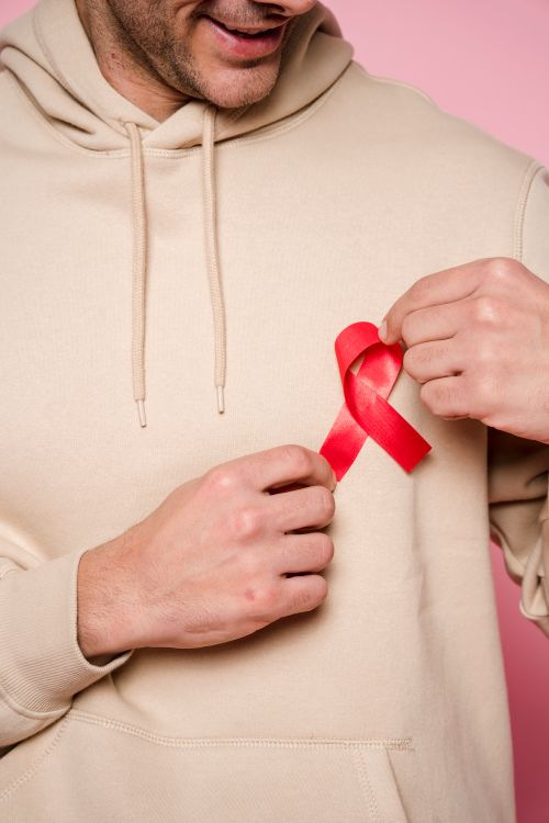 Free Man in hoodie holding red ribbon symbolizing awareness and support. Stock Photo