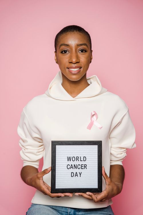 Free African American woman supporting World Cancer Day with a pink ribbon. Stock Photo
