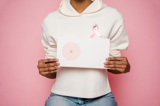 Close-up of woman holding pink ribbon card, promoting breast cancer awareness.