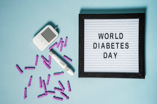 Top view of lancets for blood glucose meter placed near glucometer and letter board with World Diabetes Day inscription