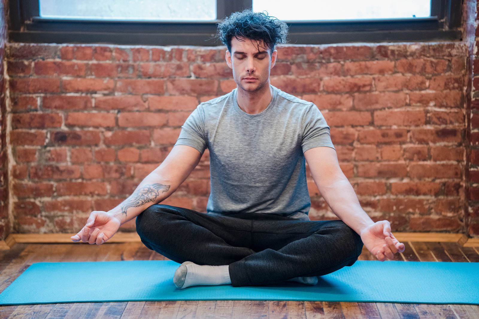 Man sitting cross-legged in easy pose meditating on a yoga mat with eyes closed