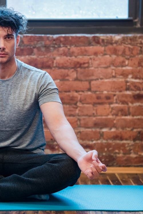 Free Man meditating in Easy sit position on sports mat Stock Photo