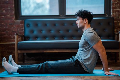 Free Side view full body of male sitting on sports mat while having break in training Stock Photo