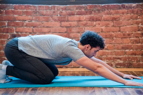 Side view of focused male doing Uttana Shishosana to stretch spine and shoulders during yoga session