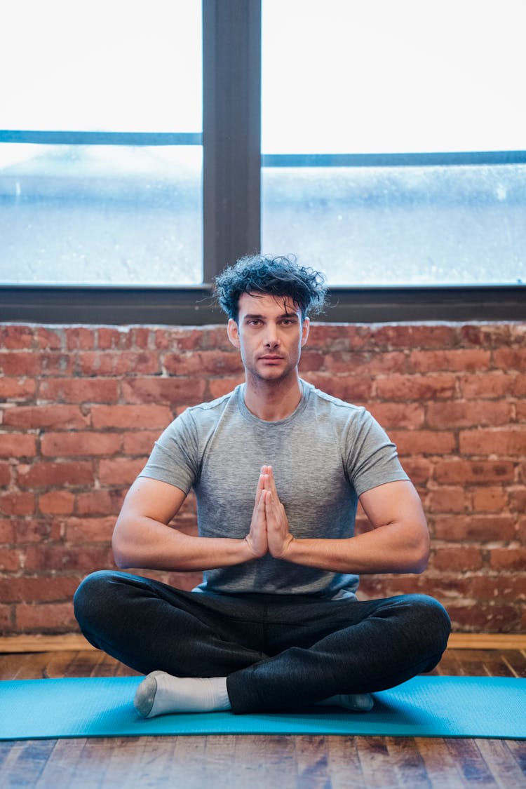 Meditating Man Sitting With Crossed Legs And Namaste Gesture