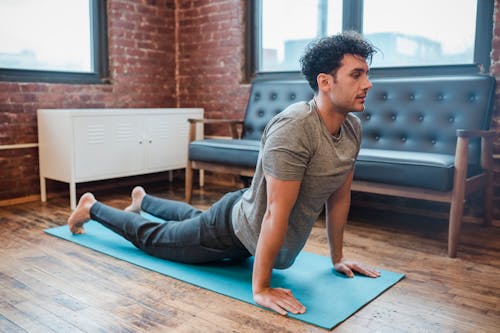 Man In Grijs T Shirt Met Ronde Hals En Blauwe Denimjeans Zittend Op Blauwe Yogamat