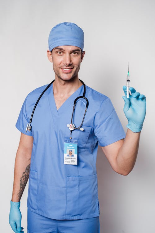 Cheerful tattooed doctor with syringe in uniform