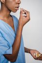 Black woman in blue patient gown taking pills