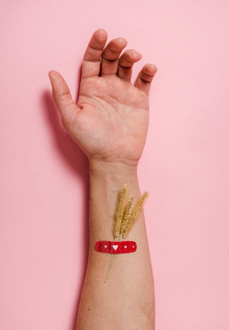Close-up of an arm with wheat and a bandage, symbolizing healing and nature.