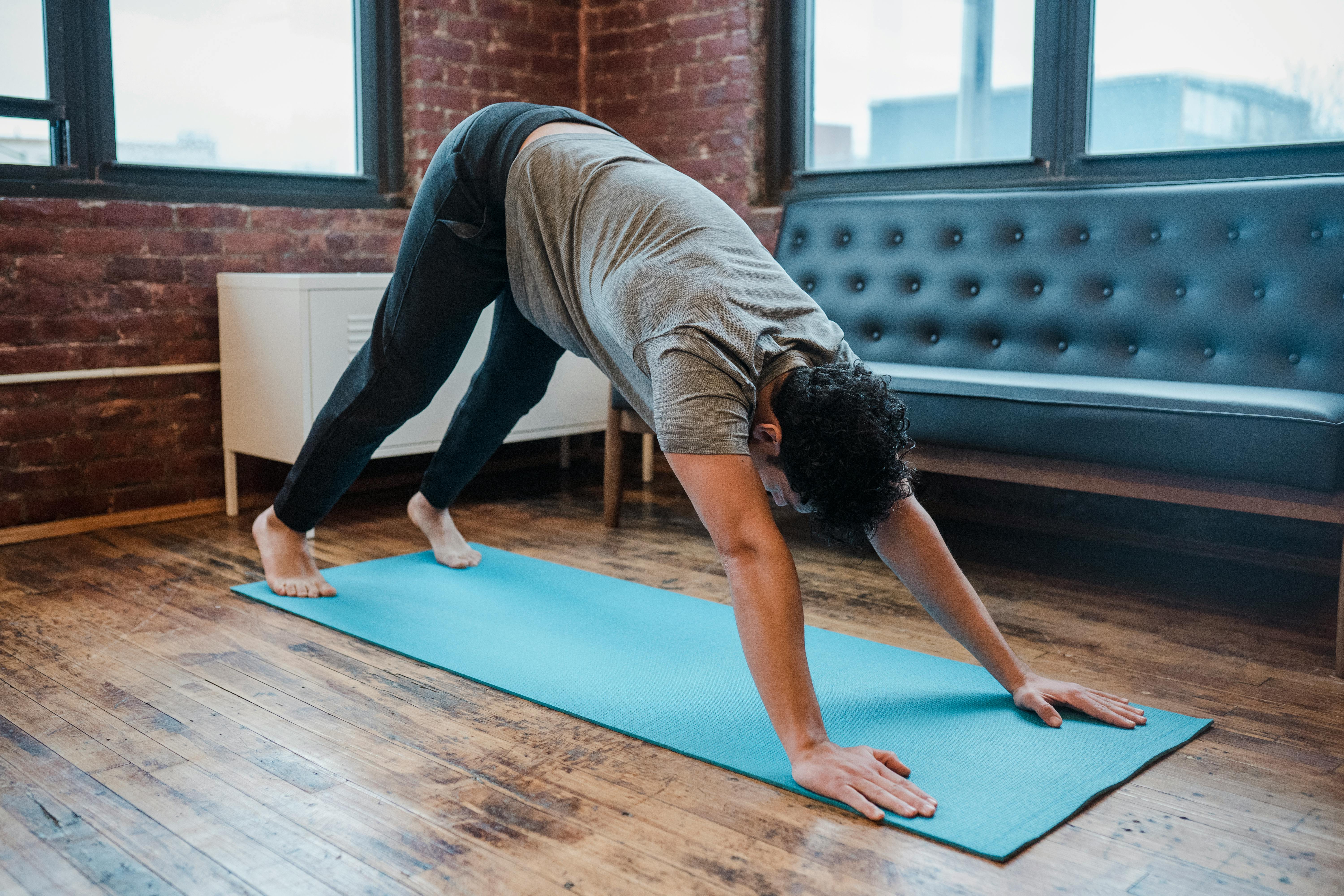 Man doing yoga in downward facing dog pose on mat · Free Stock Photo