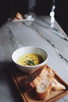 Warm soup served with bread on a stylish marble table, perfect for cozy dining.