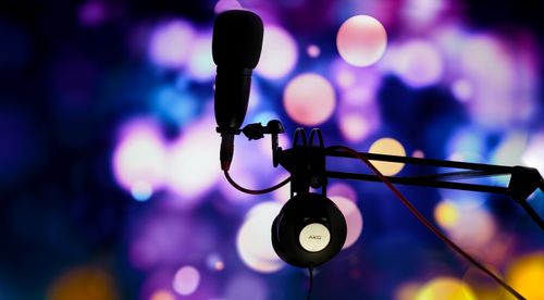 Free A studio microphone and headphones in silhouette against a vibrant bokeh background. Stock Photo