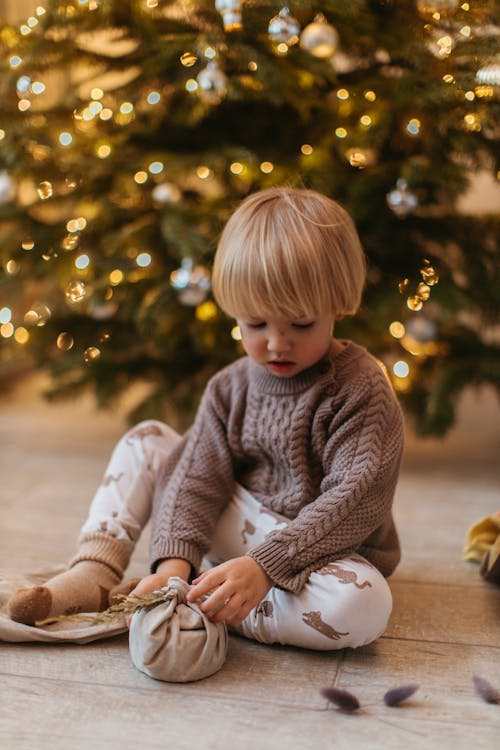 A Child Opening a Present in Front of a Christmas Tree