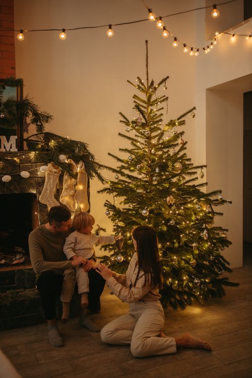 Free Warm family gathering around a decorated Christmas tree with lights. Stock Photo