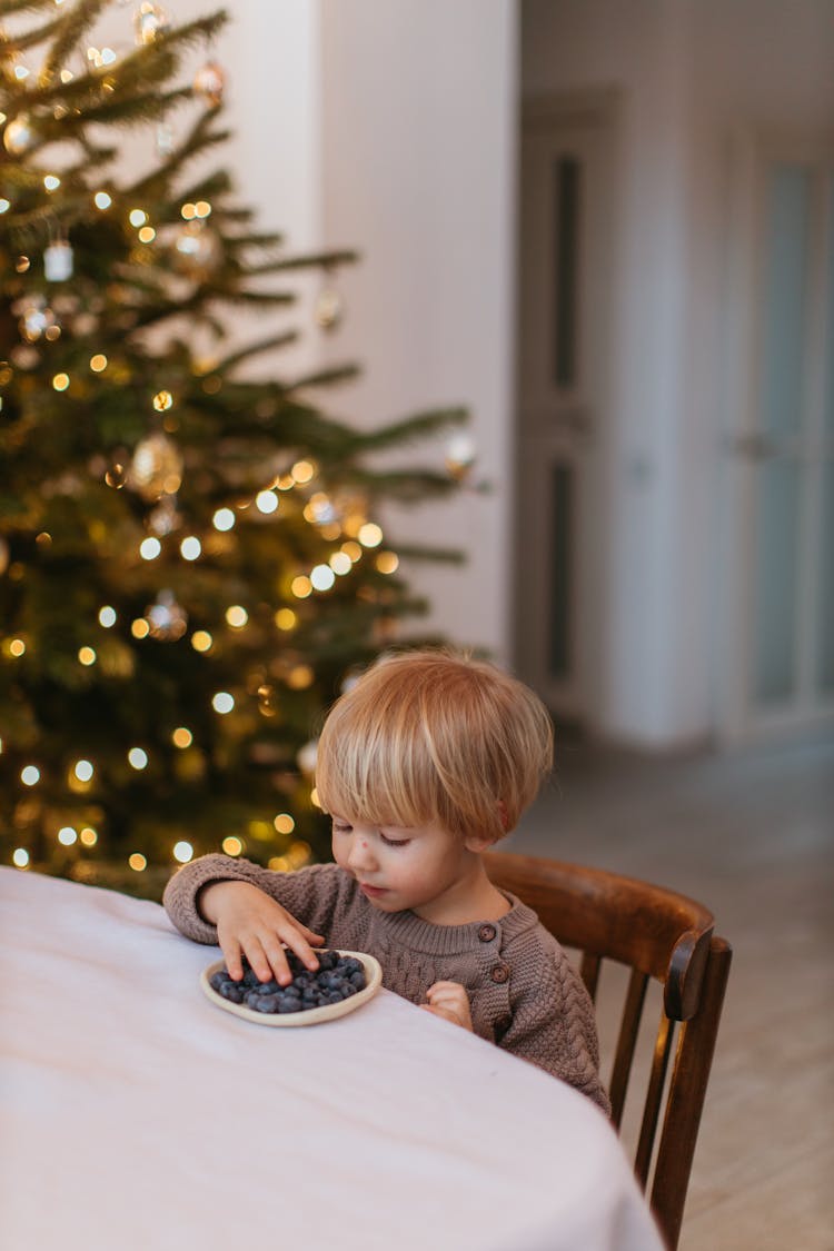 A Boy Eating Blueberries On The White Table