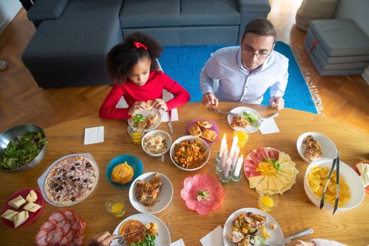 Father and daughter enjoying a diverse meal at home in Portugal.