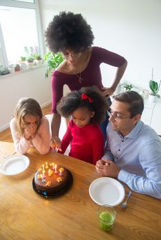 A family enjoying a birthday celebration with cake and candles indoors in Portugal.