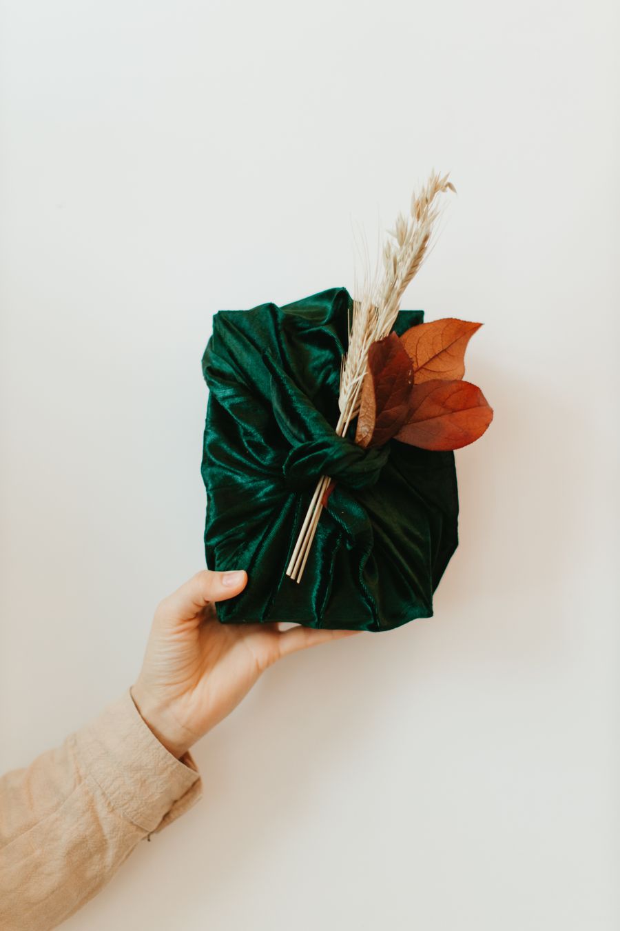 Hand holding a gift wrapped in dark green fabric