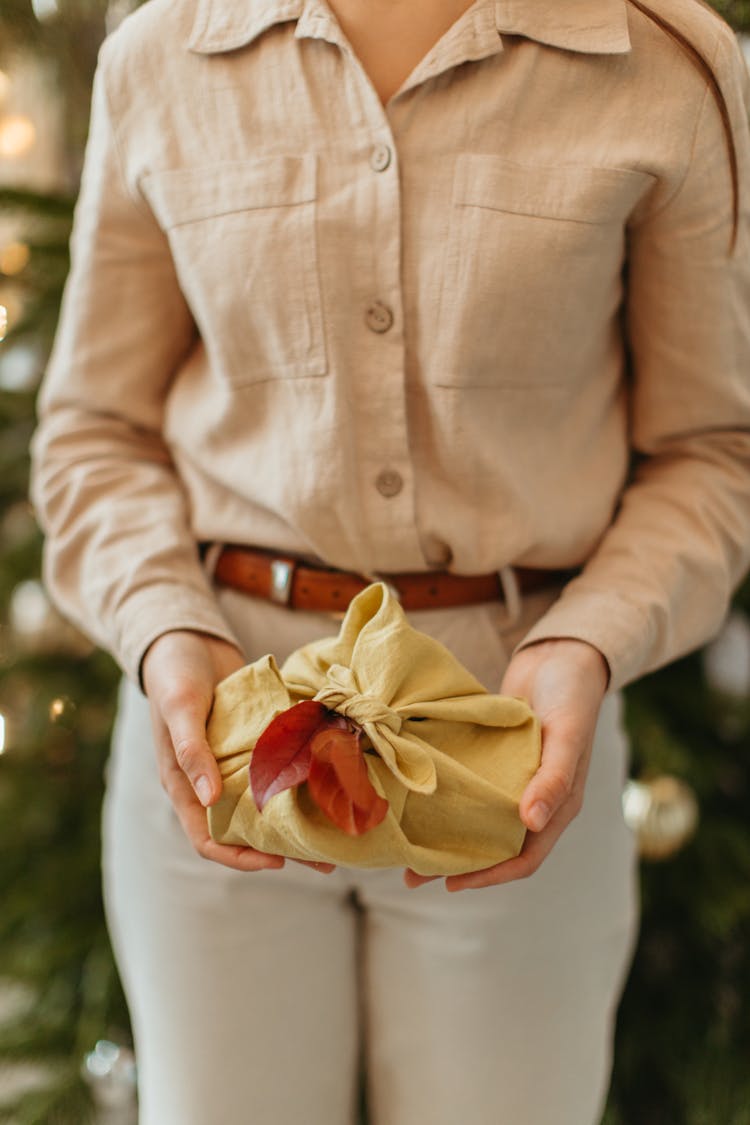 Present Wrapped With Yellow Fabric Held By A Person 