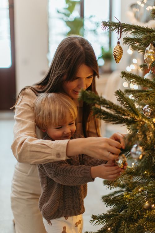 Free A mother and her son joyfully decorate a Christmas tree together, creating festive memories. Stock Photo