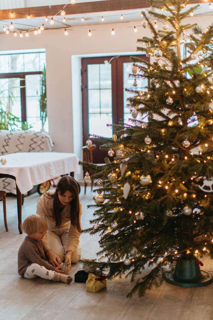 Mother And Child Sitting Beside The Christmas Tree