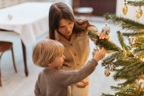 Woman and  a Boy Decorating a Christmas Tree