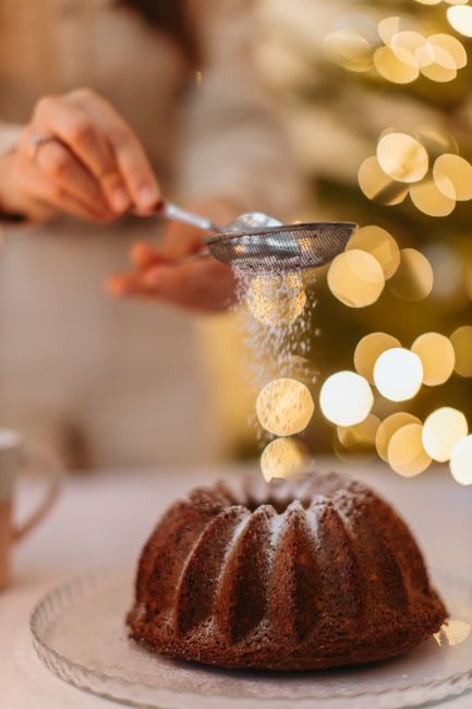 Homemade chocolate chiffon cake being dusted with sugar for a festive touch.