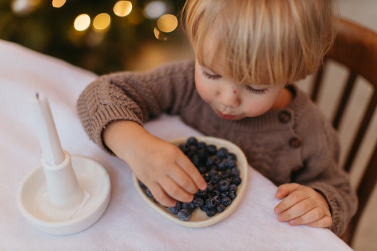 A Blonde Kid Eating Blueberries 