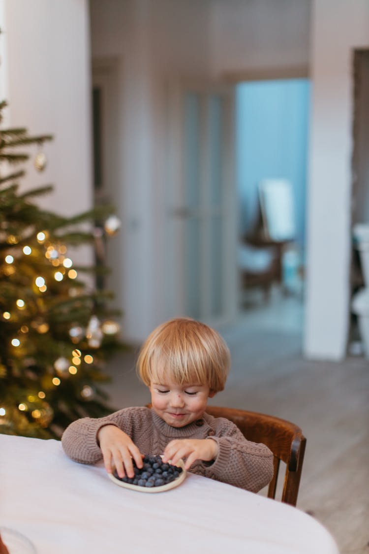 A Child Eating Blueberries On A Table