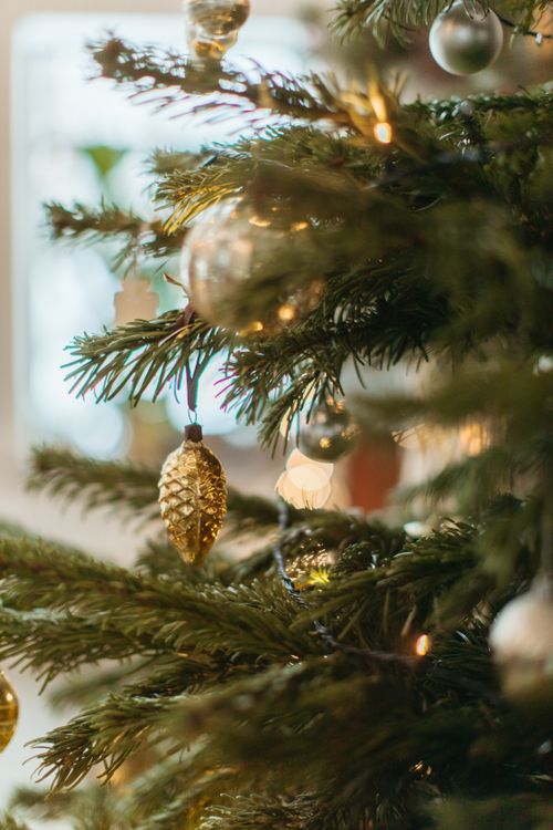 Free Elegant close-up view of decorated Christmas tree with golden ornaments and glowing lights. Stock Photo