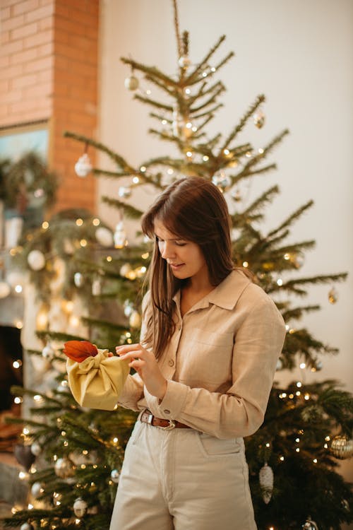 A Woman Holding a Gift near Christmas Tree