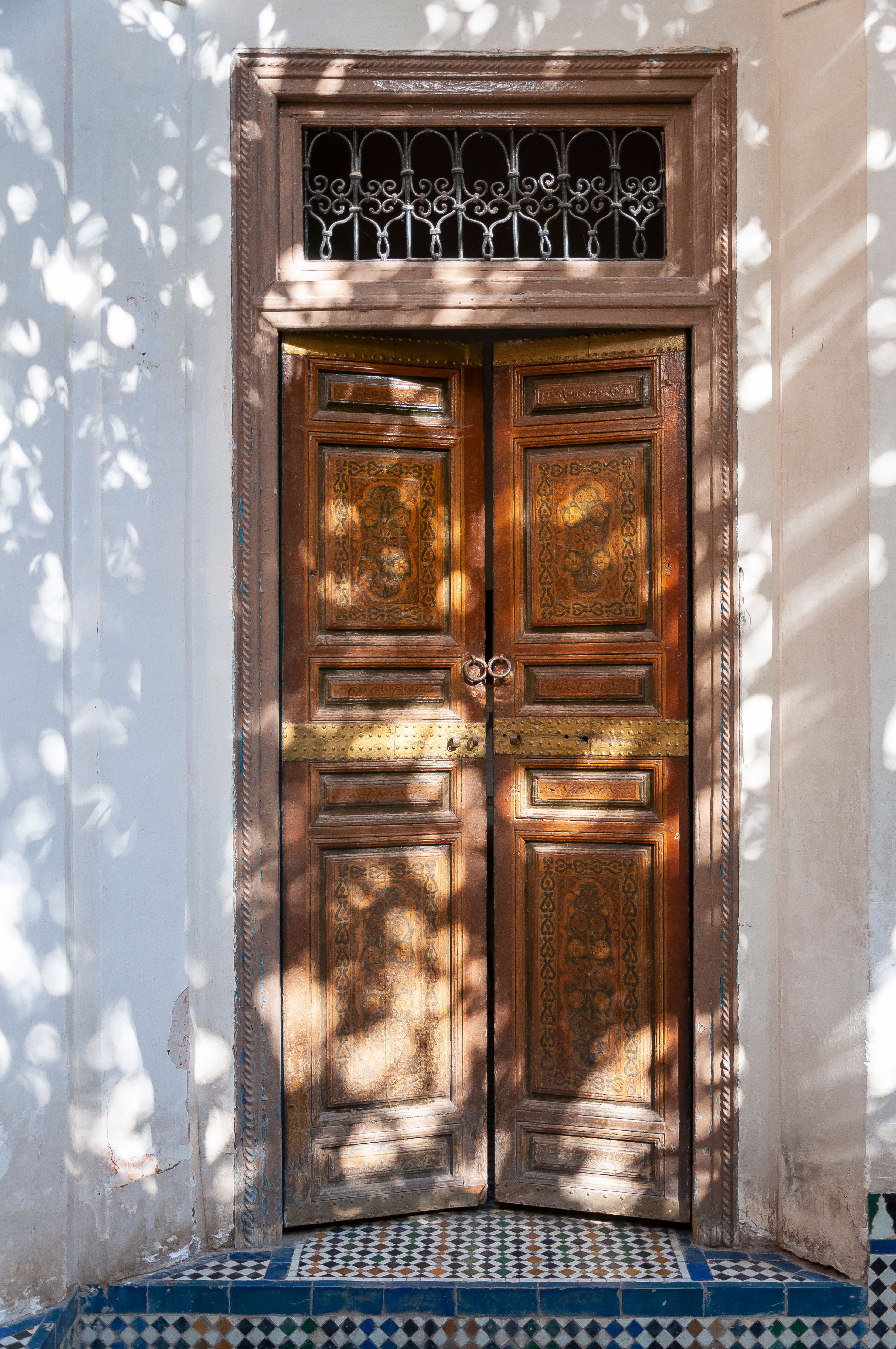 Ornamental wooden door and zellij tile covered floor at porch of old residential house on sunny day